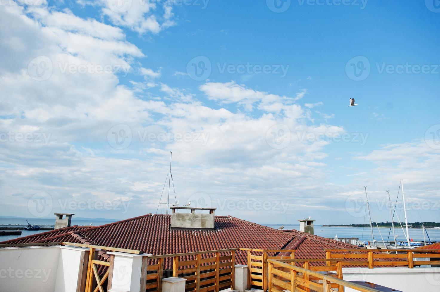 toit avec maisons en tuiles orange du vieux port nesebar, bulgarie. mouette volante. photo