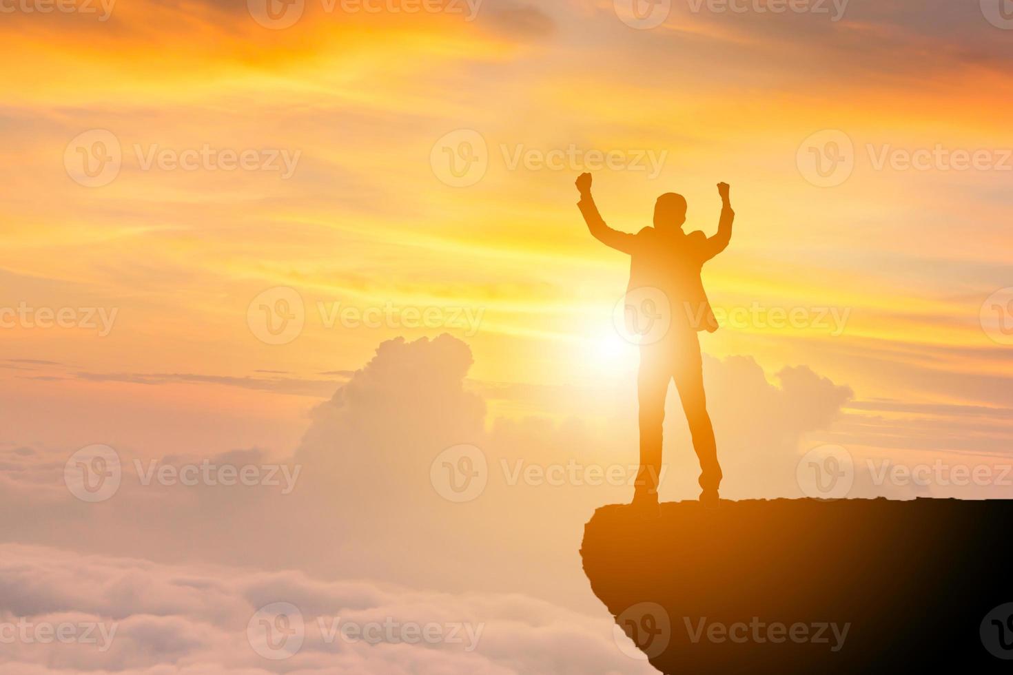 silhouette d'homme d'affaires célébration succès bonheur sur fond de ciel de soirée au coucher du soleil au sommet d'une montagne avec chemin de détourage, sport et concept de vie active. photo