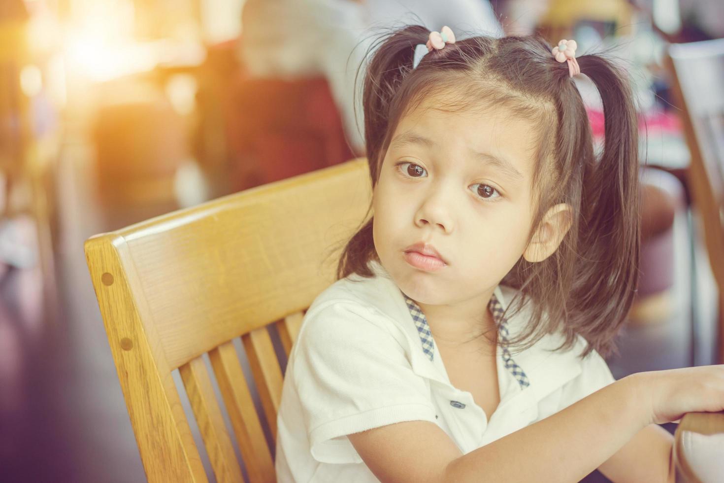 portrait d'une belle petite fille asiatique assise dans un café et regardant la caméra. photo