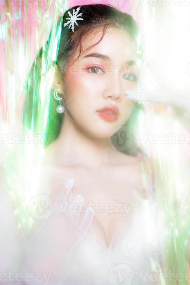 jeune femme asiatique avec un beau visage porter une robe glamour pose entourée d'une fête de rideau arc-en-ciel. concept de personnes, vacances, émotion et glamour. photo