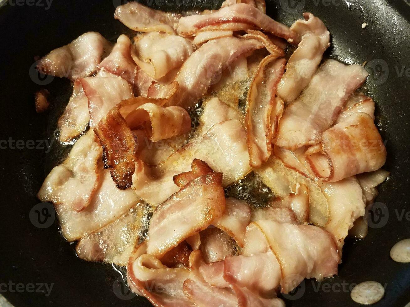 cuisson du bacon dans une poêle ou une poêle sur la cuisinière photo