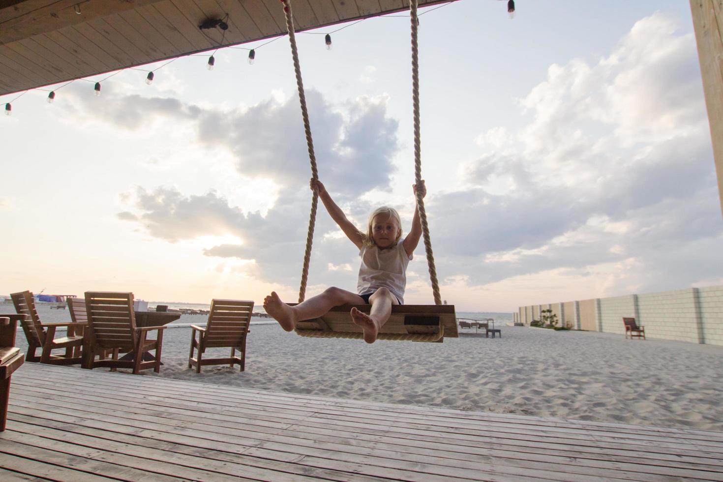 petite fille blonde profiter de la balançoire sur la plage, vacances d'été photo