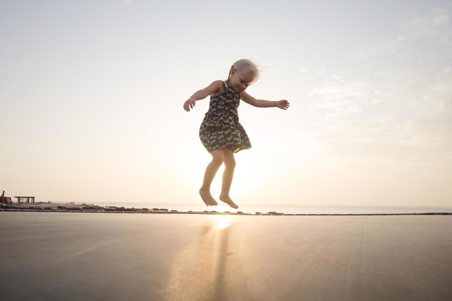 petite fille saute et passe du bon temps sur le trampoline en été photo