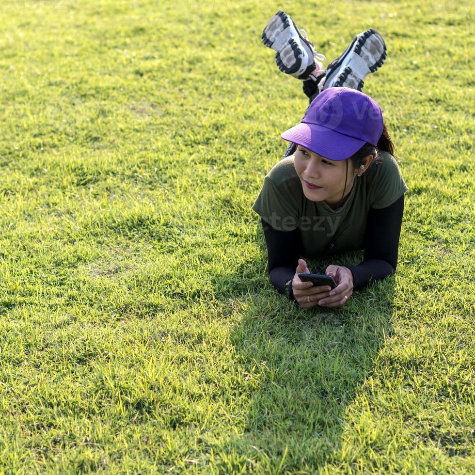 femme portant une casquette, se reposant sur une pelouse. photo