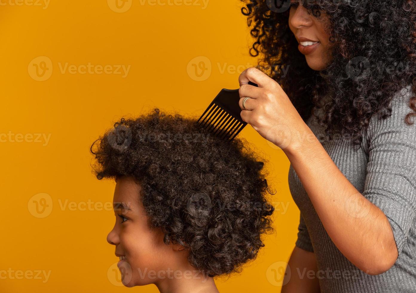 jeunes afro-américains peignant les cheveux isolés. fourchette pour peigner les cheveux bouclés. fond jaune. photo