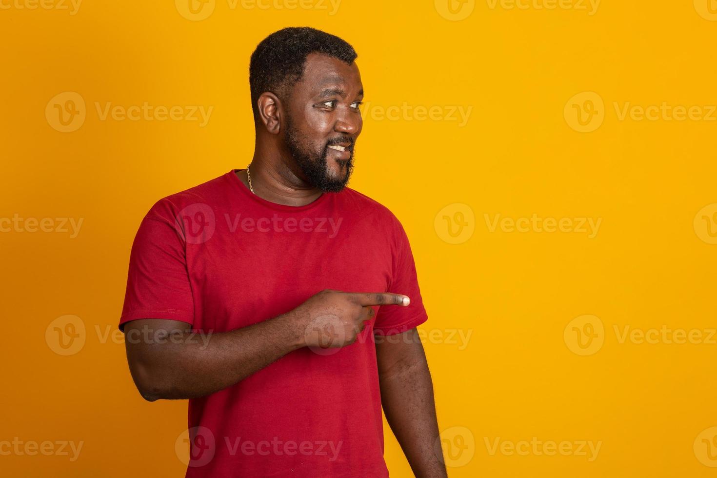 un homme positif à la peau foncée a une expression joyeuse et un large sourire avec des dents blanches, étant de bonne humeur, isolé sur un mur de studio jaune avec espace de copie. mec brésilien d'âge moyen. photo