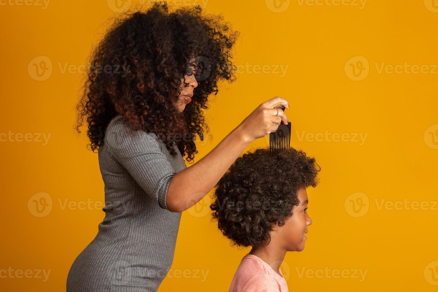 jeunes afro-américains peignant les cheveux isolés. fourchette pour peigner les cheveux bouclés. fond jaune. photo