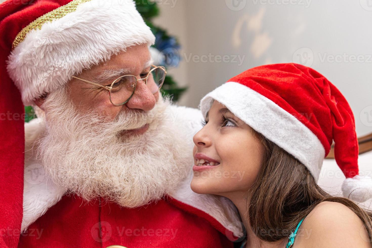 le père noël offrant une boîte-cadeau à une petite fille. réveillon de noël, livraison de cadeaux. photo