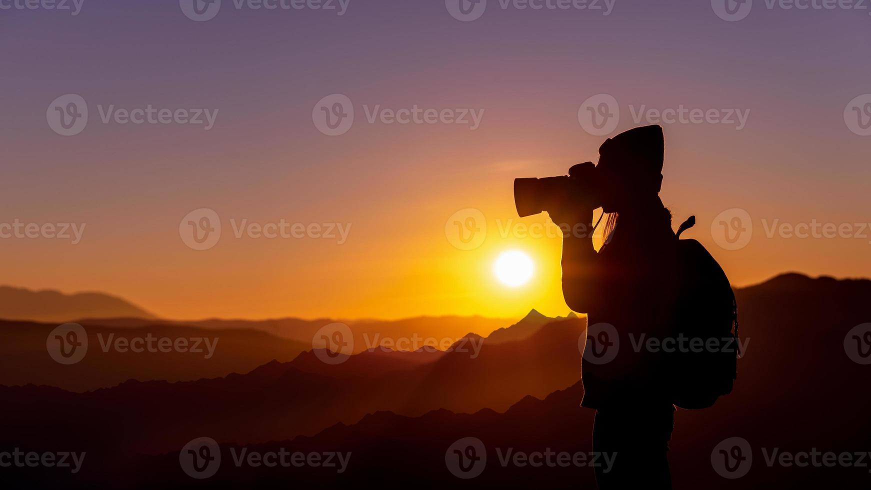 jeune hipster femme photographe prenant une photo avec le coucher du soleil sur fond naturel de montagne.