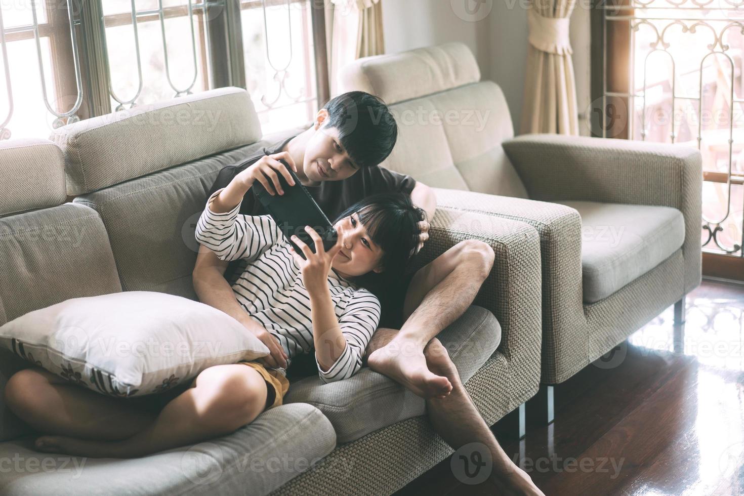 jeune couple d'amoureux asiatique adulte assis sur un canapé et jouer à un jeu de style confortable à l'intérieur le jour. photo
