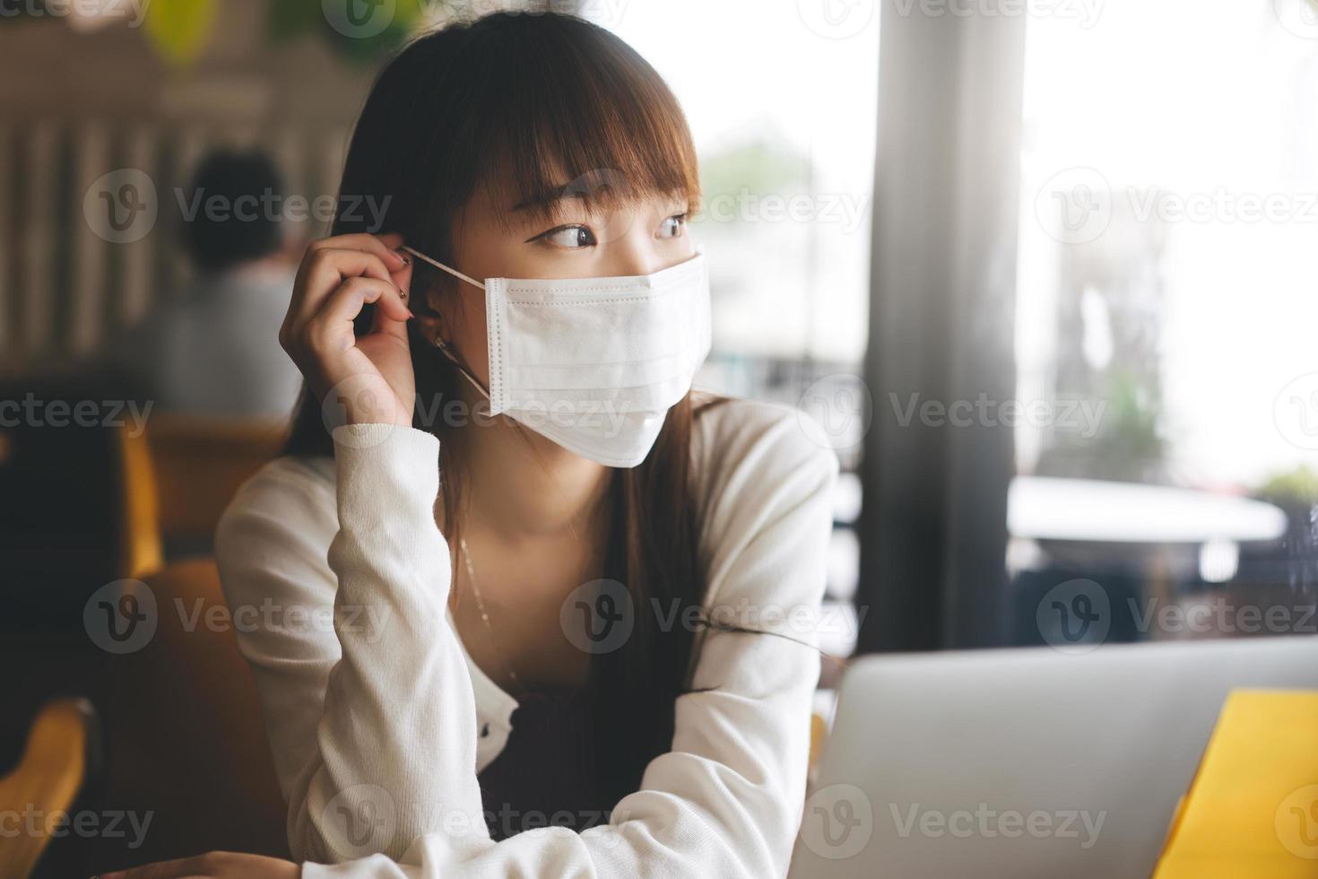 jeune femme asiatique adulte avec masque protecteur pour le virus covid 19 travail et étude au café le jour. photo