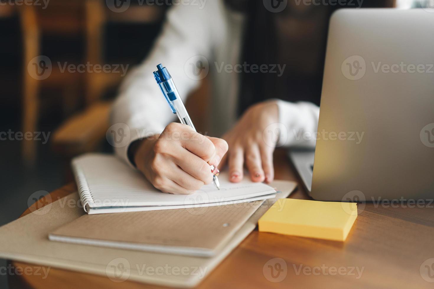 les jeunes femmes adultes écrivent à la main une note pour étudier et travailler en ligne à la table du café avec un ordinateur portable. photo