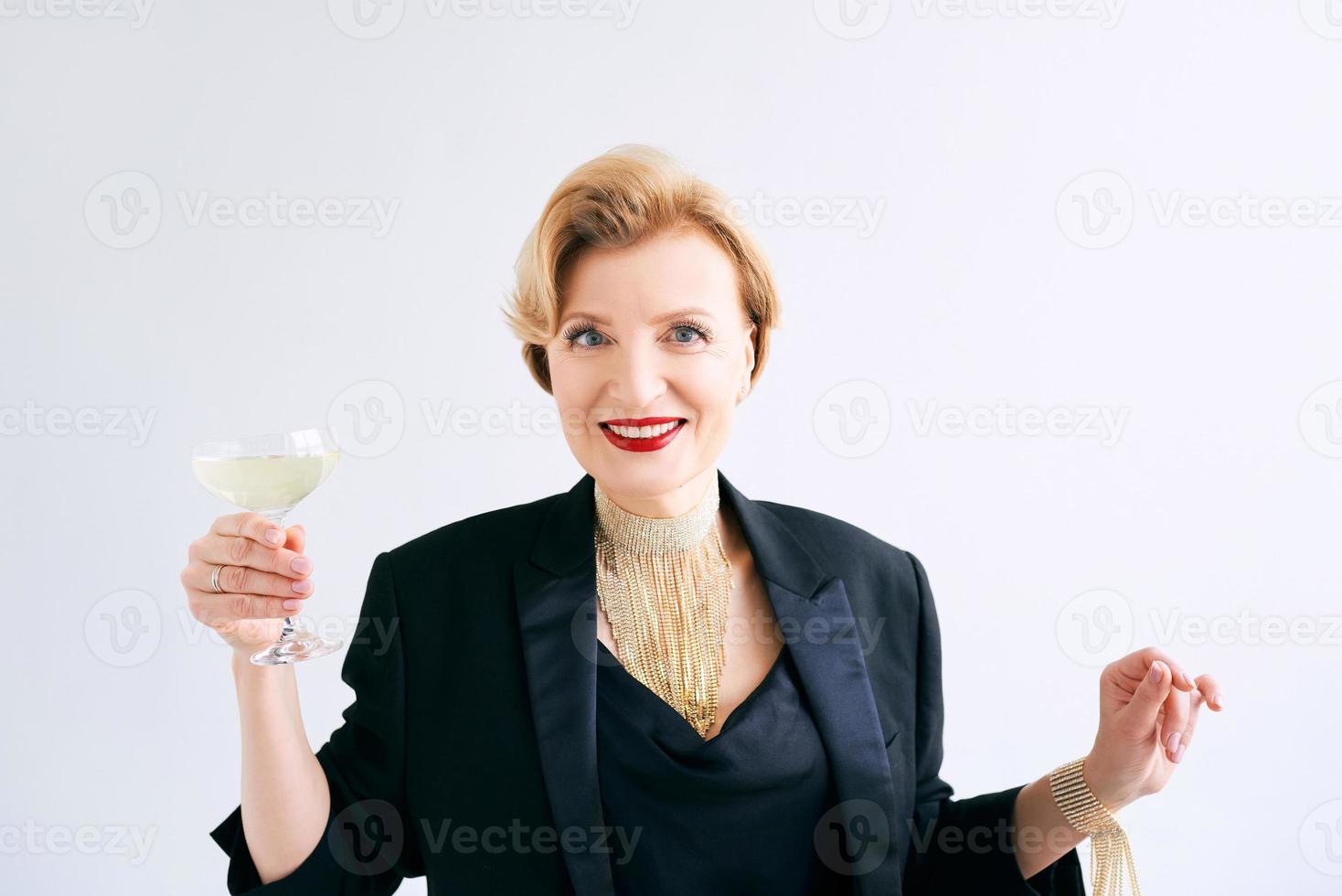 femme élégante et élégante mature en smoking avec un verre de vin mousseux. fête, célébration, concept anti-âge photo