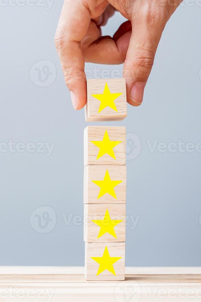 main tenant des blocs de bois avec le symbole étoile. commentaires des clients, commentaires, notation, classement et concept de service. photo
