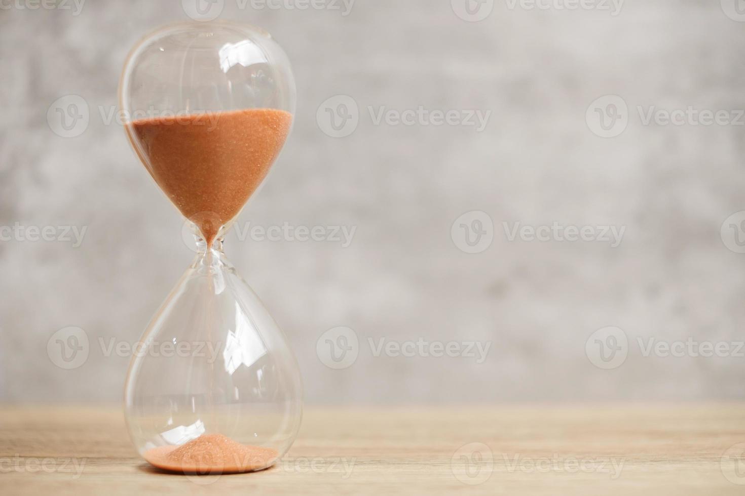 sablier sur table, sable coulant à travers l'ampoule de sablier mesurant le temps qui passe. compte à rebours, date limite, durée de vie et concept de retraite photo