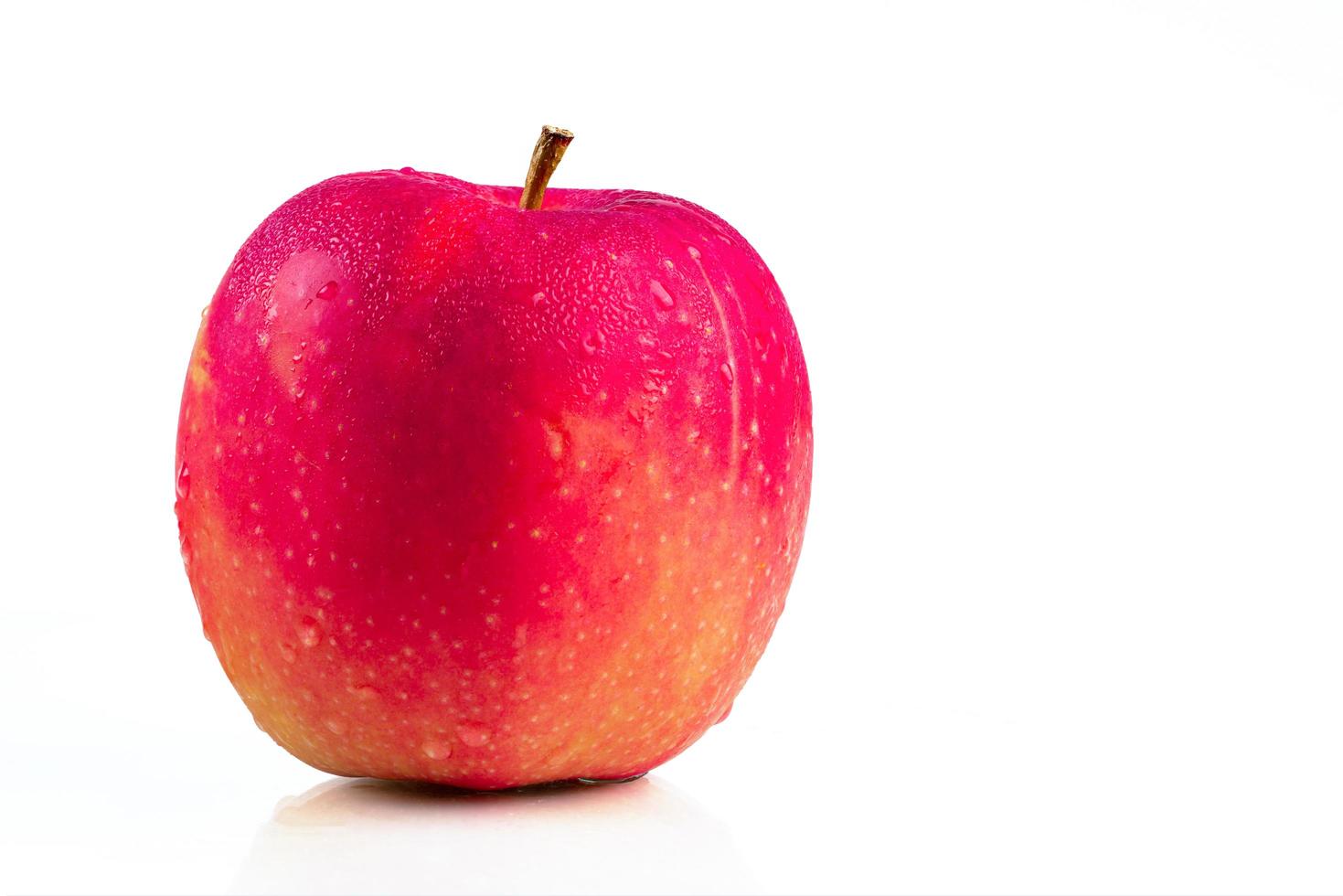 une pomme rouge avec des gouttes d'eau sur la peau isolée sur fond blanc avec espace de copie. fruits sains et concept d'aliments sains. nourriture végétalienne. photo