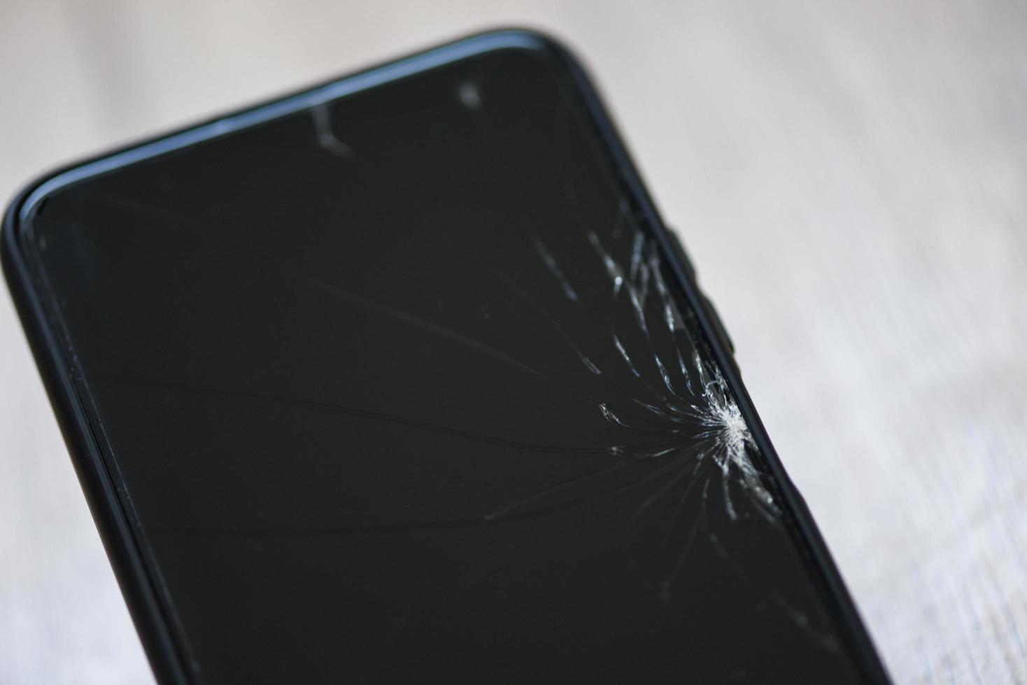 écran de verre cassé de smartphone sur fond de bois - écran cassé de téléphone portable attendez le changement d'écran de film dans le concept d'atelier de réparation photo