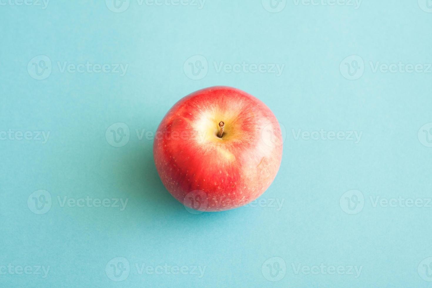 image minimaliste d'une pomme rouge sur fond bleu. photo