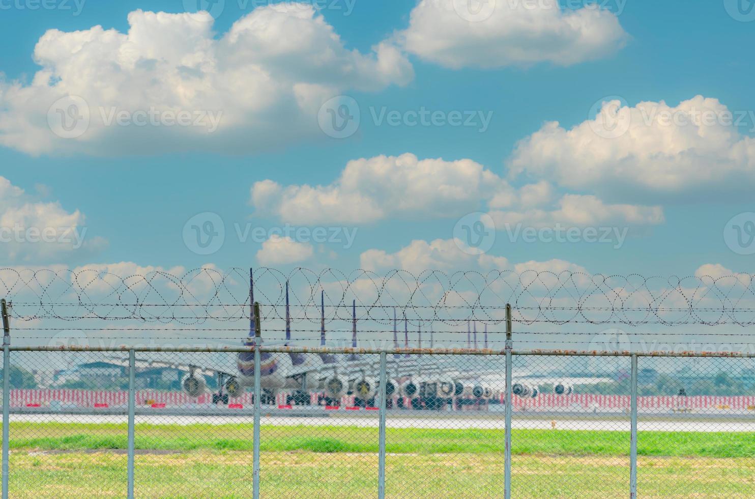 clôture métallique de l'aéroport et avion flou stationné sur le parking de l'aéroport. de nombreux avions stationnés et des vols impactés par un coronavirus. crise de l'industrie aéronautique. clôture contre le ciel bleu. photo