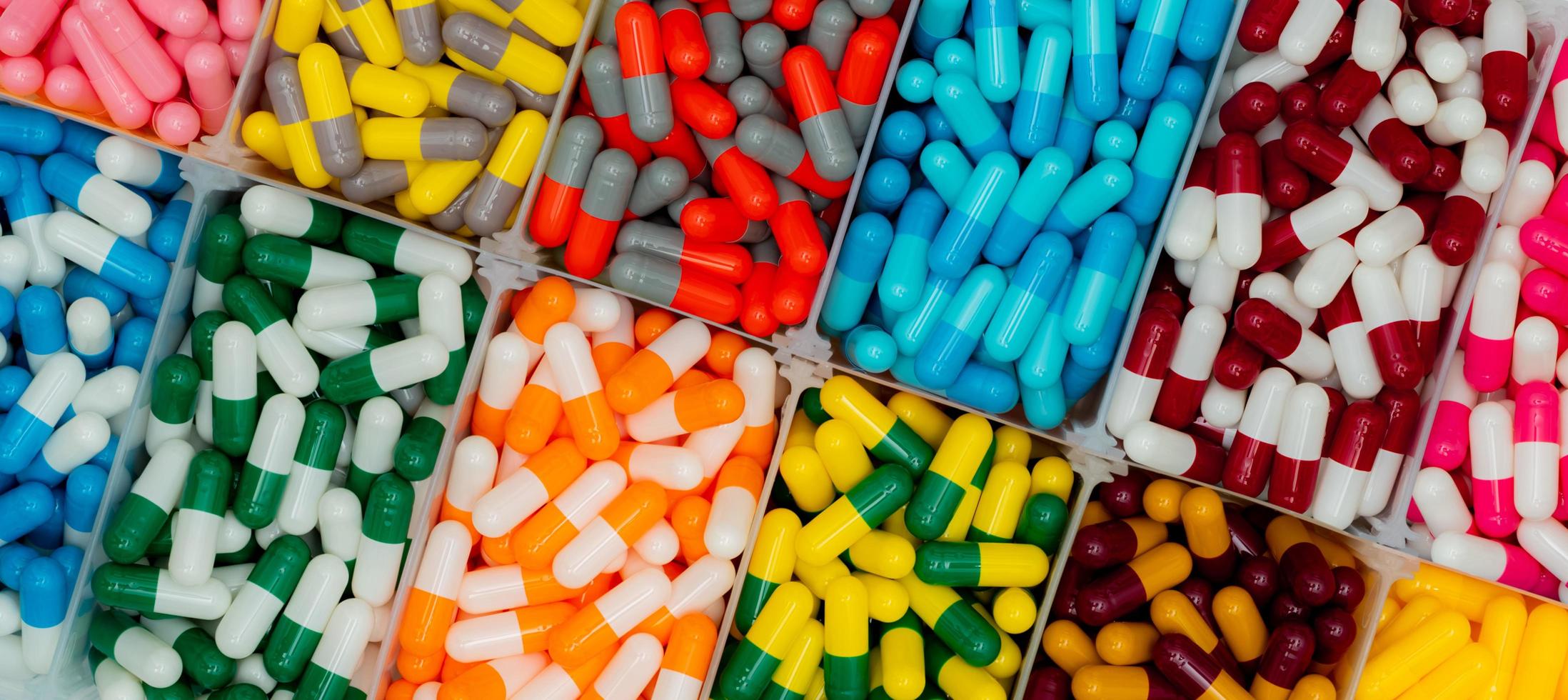 vue de dessus de pilules de capsule colorées dans une boîte en plastique. antibiotiques, analgésiques, vitamines et suppléments gélules. industrie pharmaceutique. infections. production de gélules. photo