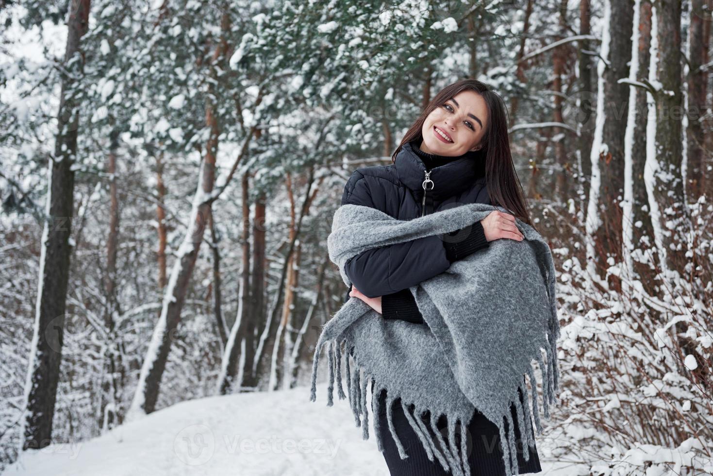 portrait de femme charmante dans la veste noire et l'écharpe grise dans la forêt d'hiver photo