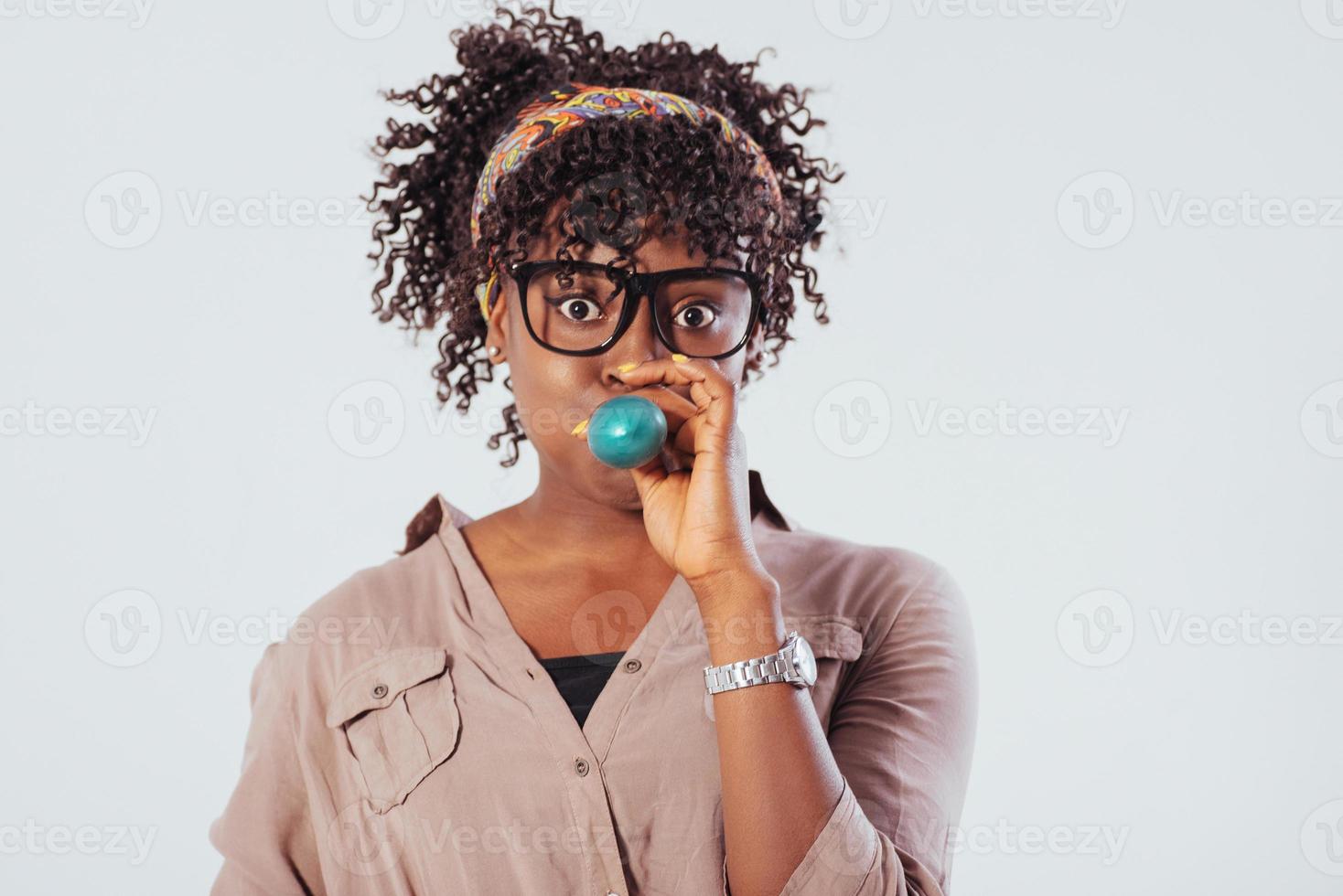 gonfle un ballon bleu. belle fille afro-américaine aux cheveux bouclés dans le studio avec un fond blanc photo