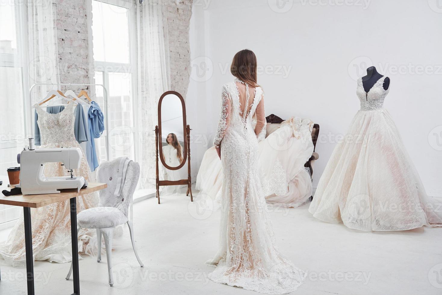 se montrer et se regarder dans le miroir. le processus d'essayage de la robe dans l'atelier de vêtements fabriqués à la main photo