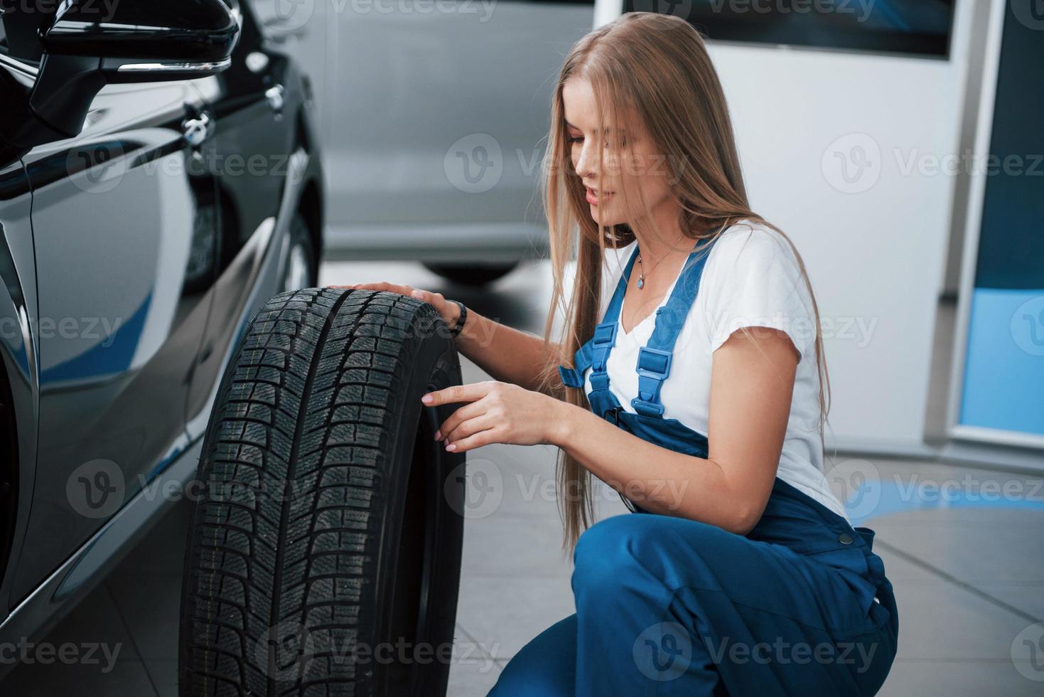 assis avec une nouvelle roue près de la nouvelle voiture de luxe parfaitement polie. prêt à remplacer photo