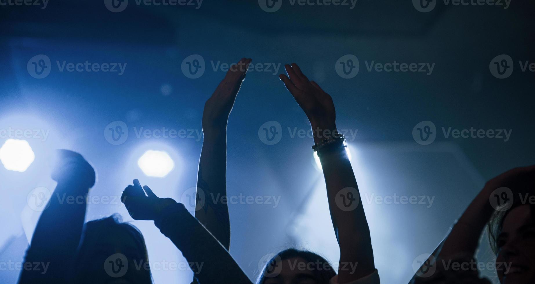 mettez vos mains en l'air. groupe de personnes qui aiment danser dans la discothèque avec de beaux éclairages photo