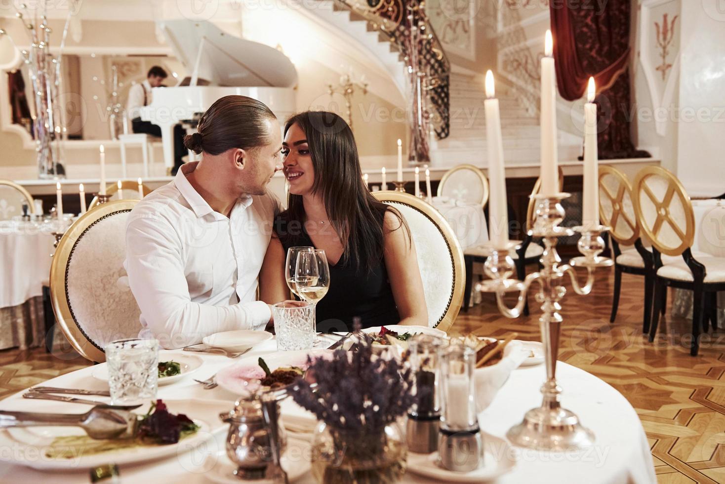 rencontre avec bougies et musique classique. un beau couple dîne romantique dans un restaurant de luxe le soir photo