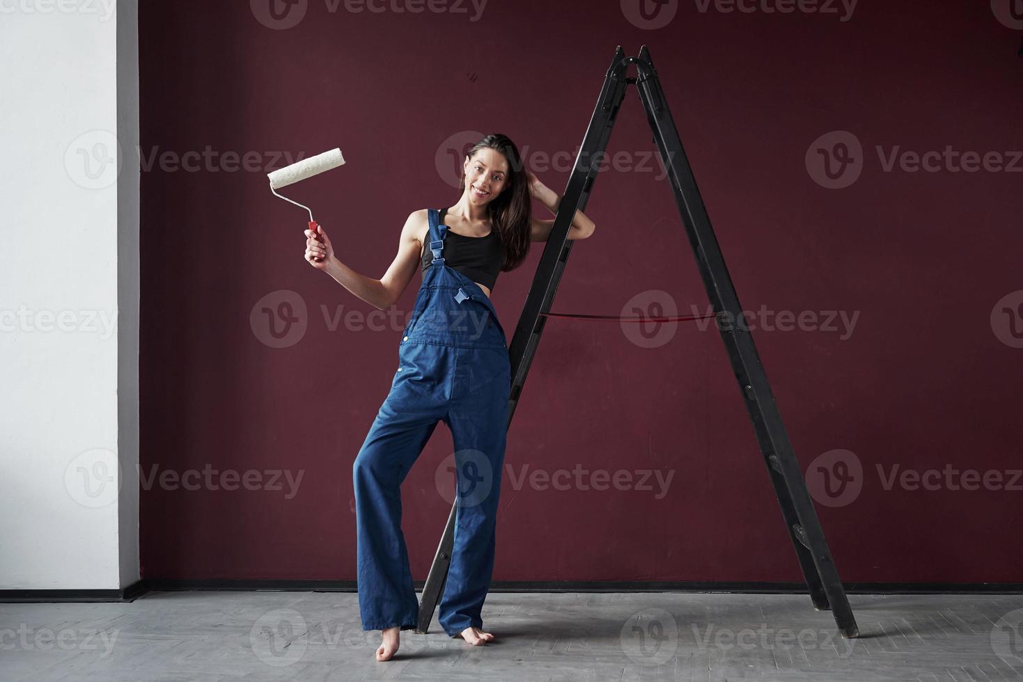 montre un rouleau blanc. jeune femme au foyer a décidé de coller du papier peint dans sa nouvelle maison dans la chambre photo