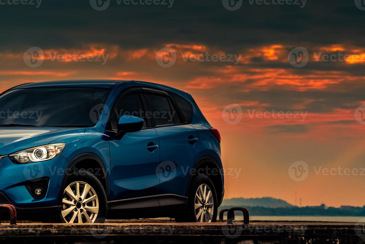 voiture suv compacte bleue au design sportif et moderne garée sur une route en béton près de la plage au coucher du soleil. technologie des voitures hybrides et électriques. place de parking. industrie automobile. fond d'affaires de soins de voiture. photo