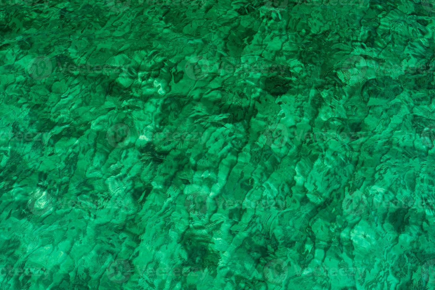 fond de texture abstraite verte d'eau de mer vert émeraude. vue de dessus de l'eau de mer verte avec un motif unique. fond vert. surface des vagues d'eau de mer sur la côte. eau turquoise en mer peu profonde. photo