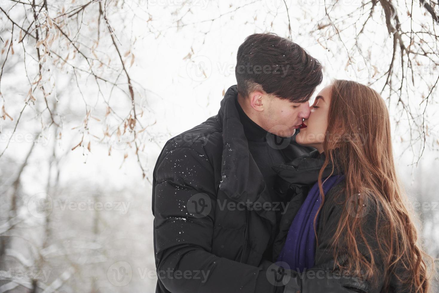 beaux bisous. magnifique jeune couple passe du bon temps ensemble dans la forêt enneigée photo