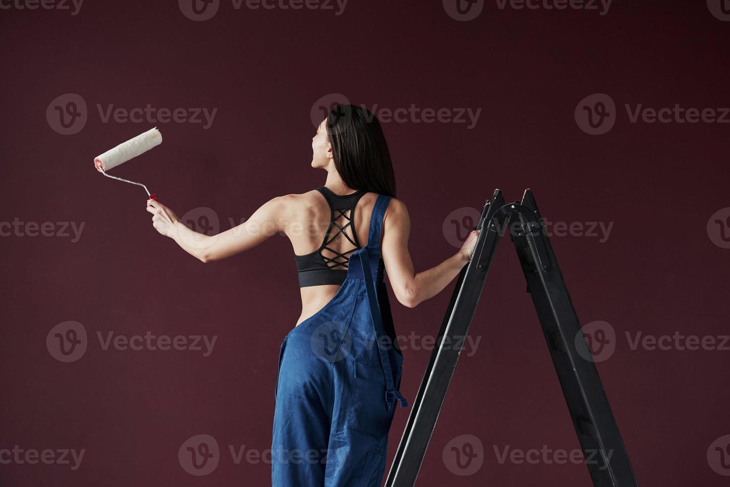 vue arrière. jeune femme au foyer a décidé de coller du papier peint dans sa nouvelle maison dans la chambre photo