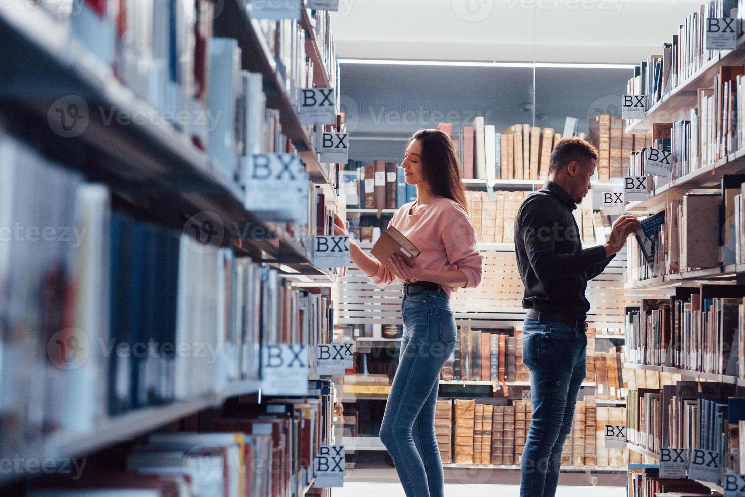 apprécier le processus. étudiants multiraciaux dans la bibliothèque à la recherche d'informations ensemble photo