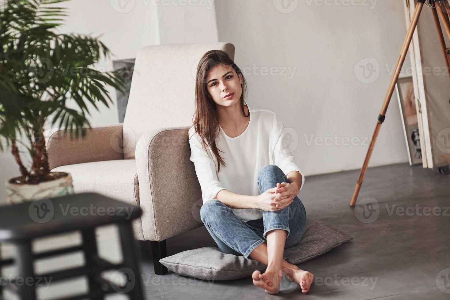 ambiance feutrée. jeune brune dans la chambre aux murs blancs et à la lumière du jour qui vient de la fenêtre photo