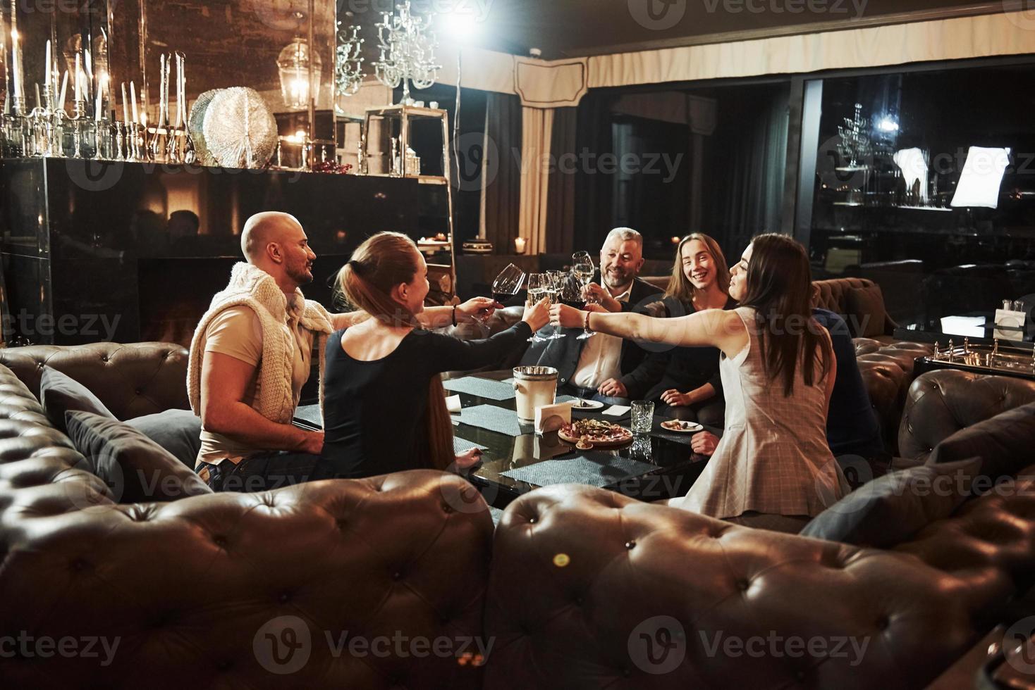 les amis de la famille passent une bonne soirée près de la cheminée dans un restaurant moderne de luxe photo