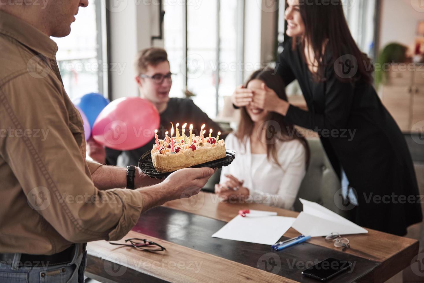 fermer les yeux de la jeune fille brune. l'un des employés fête son anniversaire aujourd'hui. des collègues amicaux décident de lui faire une surprise photo