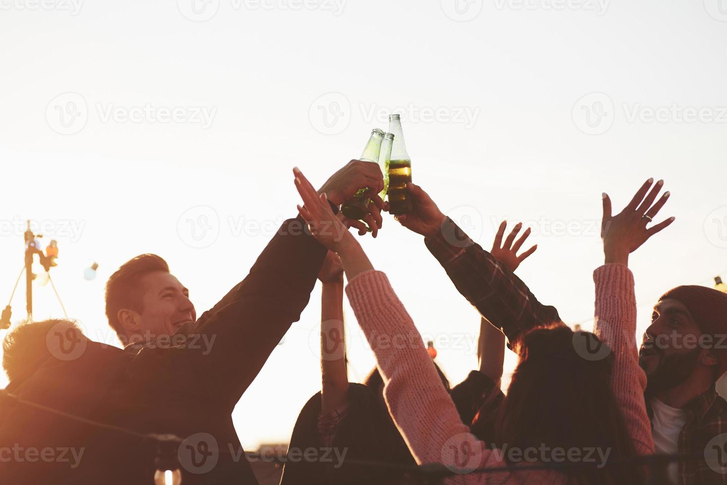 prêt pour la fête. vacances sur le toit. joyeux groupe d'amis a levé la main avec de l'alcool photo