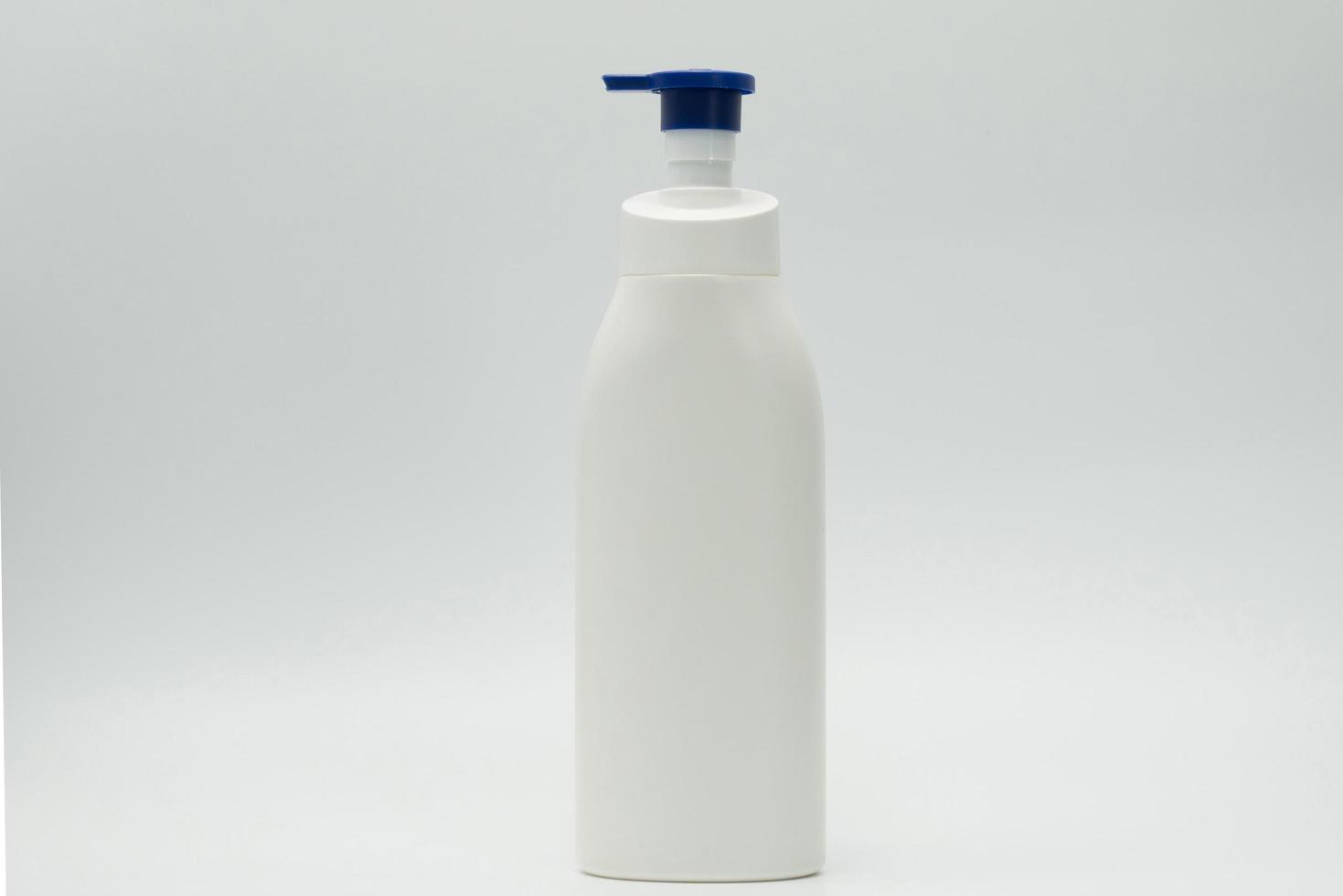 bouteille en plastique blanc cosmétique avec distributeur de pompe bleu isolé sur fond blanc avec étiquette vierge et espace de copie. bouteille de soins de la peau. lotion de soin pour le corps. paquet de pot cosmétique. bouteille de shampoing. photo