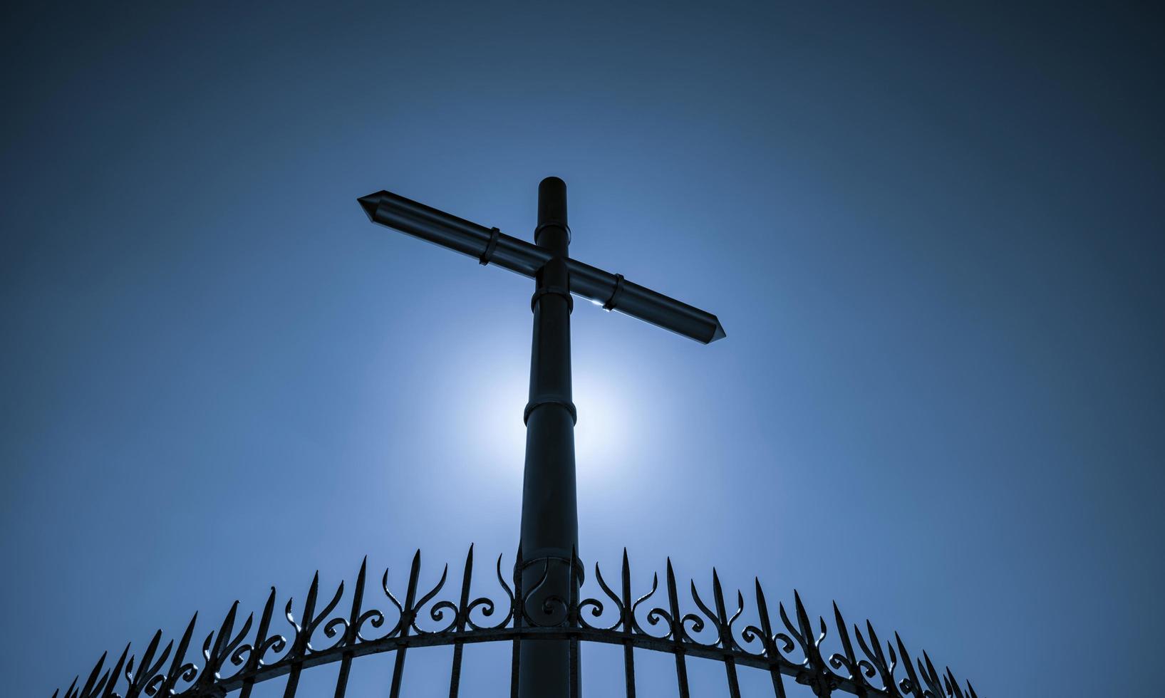 croix et clôture en acier inoxydable sur fond bleu ciel et soleil clair. crucifix de jésus christ. concept de lumière divine et de pardon. croix, symboles chrétiens. croyance en Dieu. symbole de foi. Pâques. photo