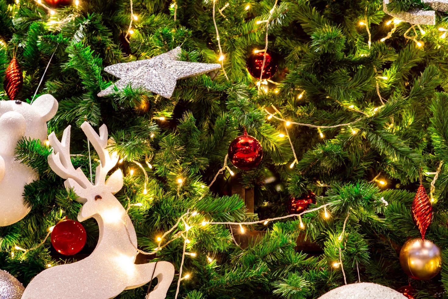 gros plan sur la décoration d'arbre de noël avec des boules rouges, dorées, argentées et blanches, une étoile argentée et un renne blanc. fond de Noël. fond de noël et bonne année. boule colorée sur le sapin de Noël. photo