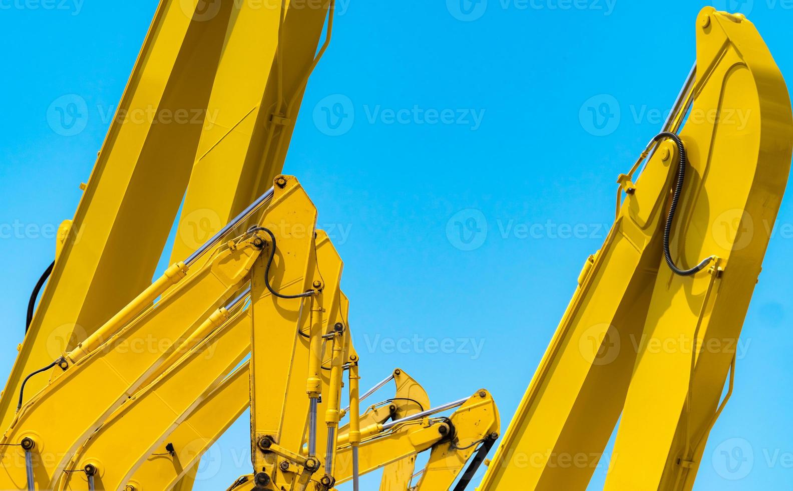 pelleteuse jaune avec bras de piston hydraulique contre ciel bleu clair. machine lourde pour l'excavation sur chantier. machines hydrauliques. énorme bulldozer. industrie des machines lourdes. génie mécanique. photo