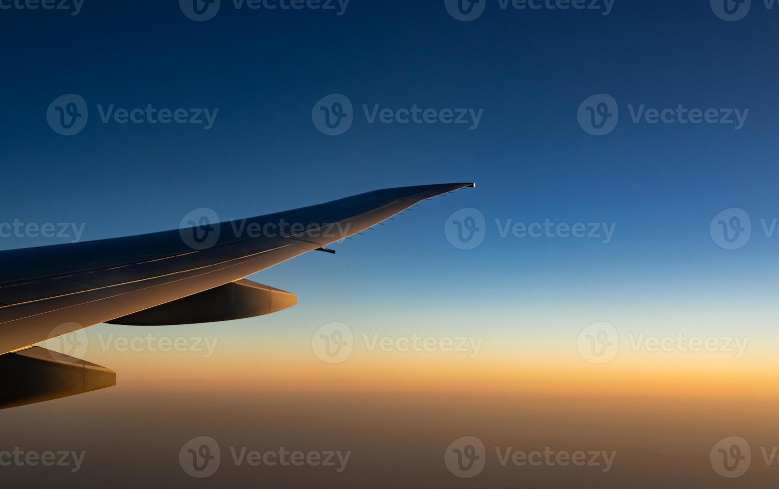 aile d'avion au-dessus de la ville. avion volant sur le ciel bleu. vue panoramique depuis la fenêtre de l'avion. vol d'une compagnie aérienne commerciale le matin avec la lumière du soleil. aile d'avion au-dessus des nuages. concept de mécanique de vol. photo