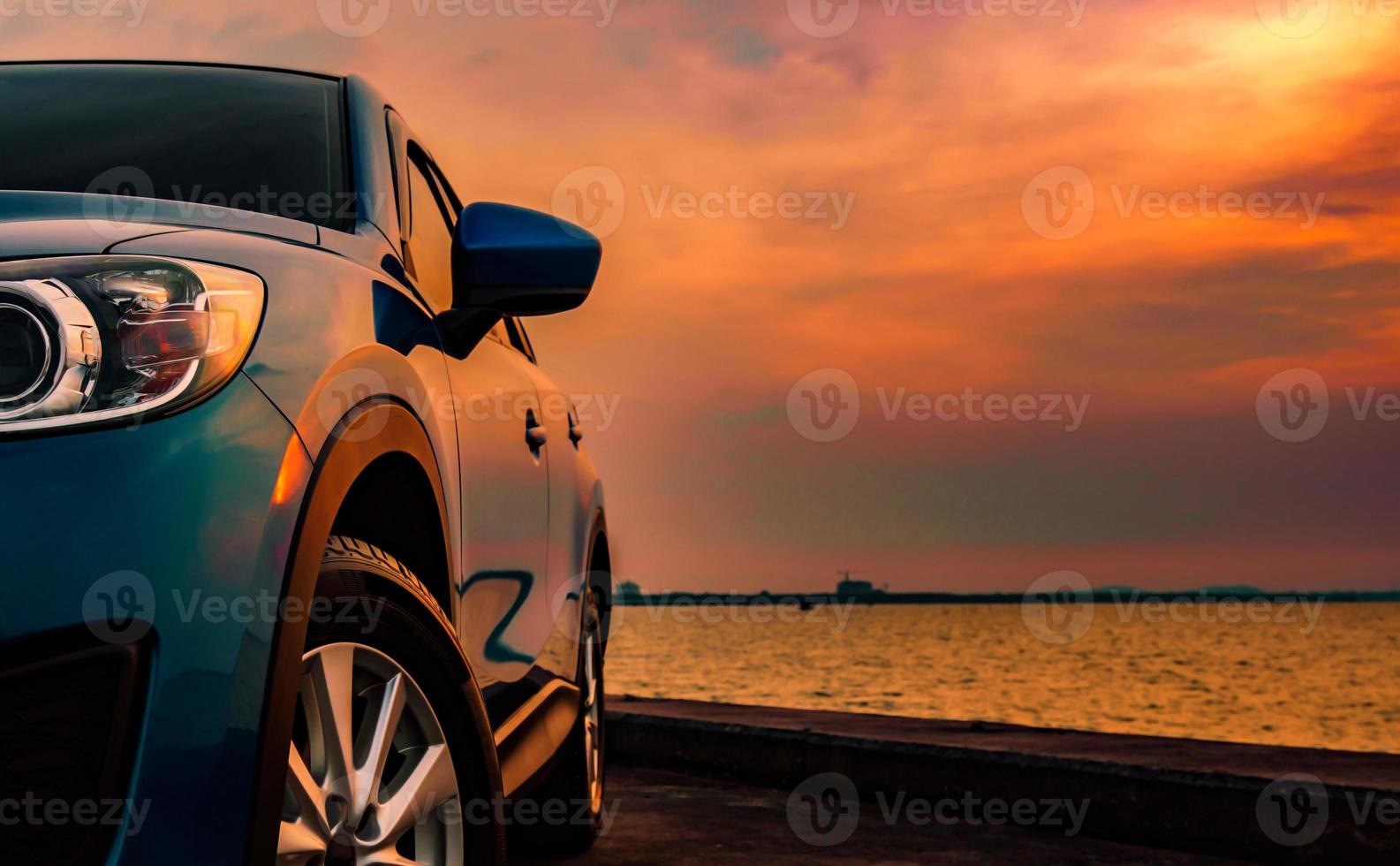 voiture suv compacte bleue au design sportif et moderne garée sur une route en béton au bord de la mer au coucher du soleil. technologie respectueuse de l'environnement. concept de réussite commerciale. photo