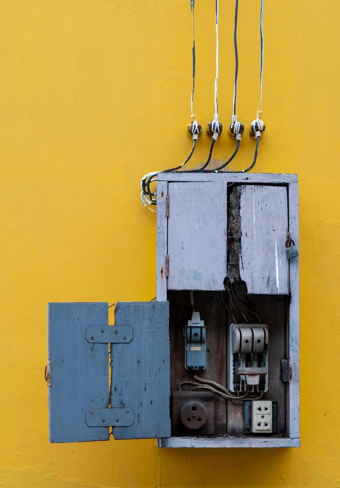 boîte en bois, équipement de commande électrique dans l'usine sur fond de mur de béton vintage jaune. découpe manuelle avec un design ancien. sécurité dans le concept industriel de la maison et de l'usine. photo