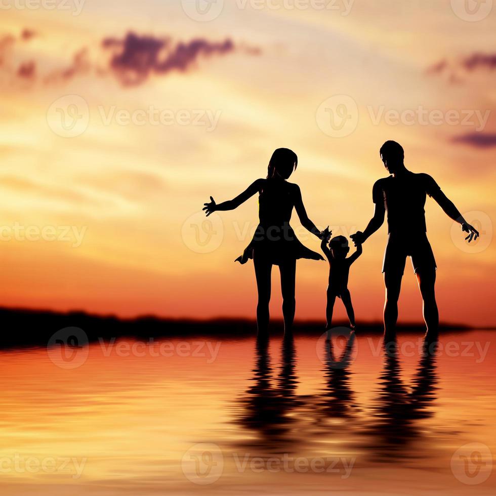 famille heureuse marchant ensemble main dans la main au coucher du soleil. mère, père, enfant. photo