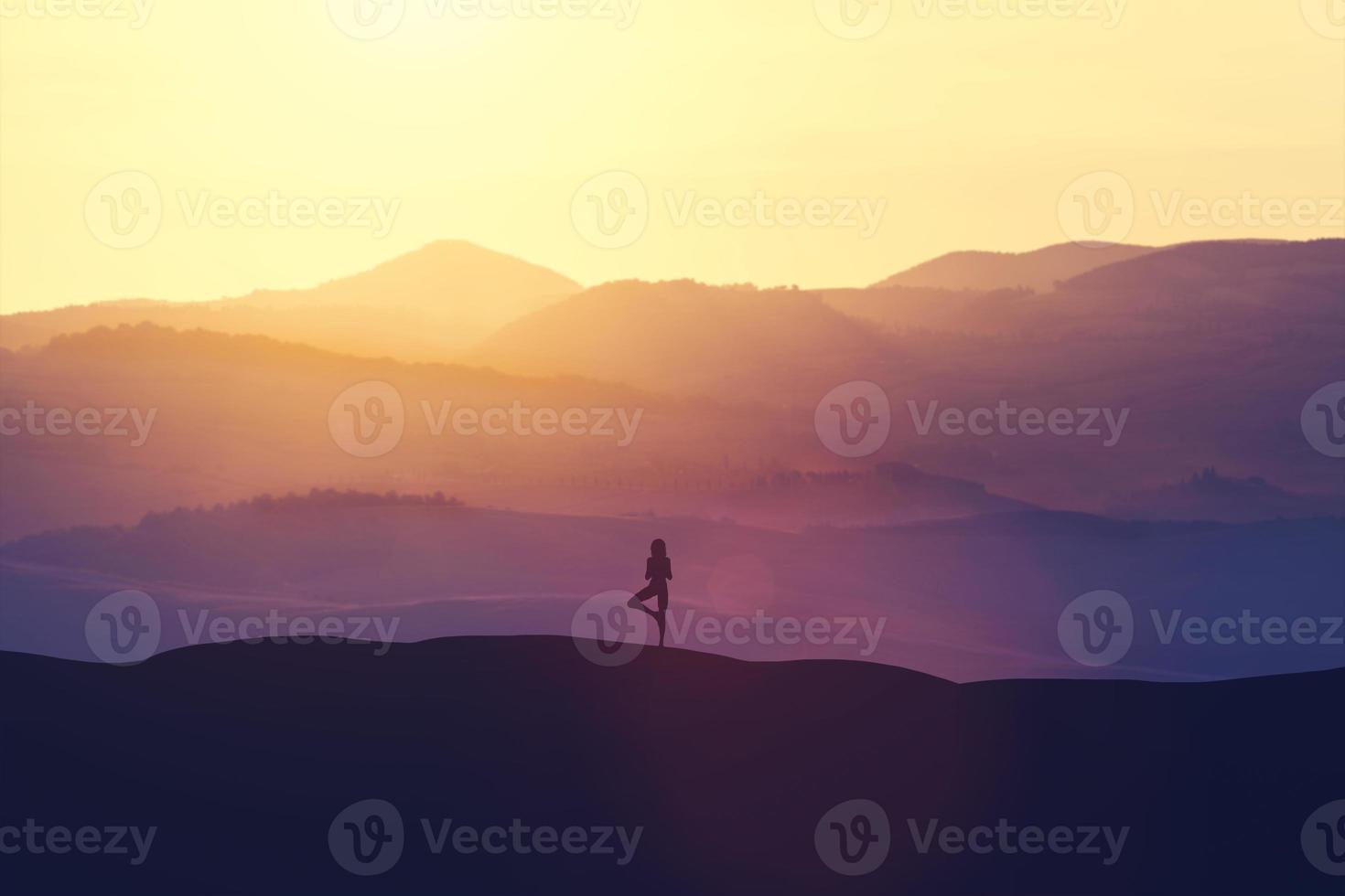 femme debout sur la colline, pratiquant le yoga. photo