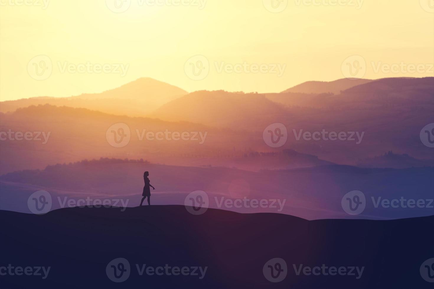femme célibataire marchant sur la colline pendant le coucher du soleil. photo